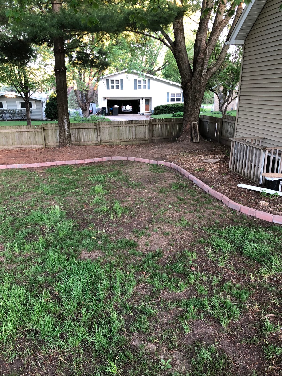 Brick-edged garden bed with bare soil along the walkway
