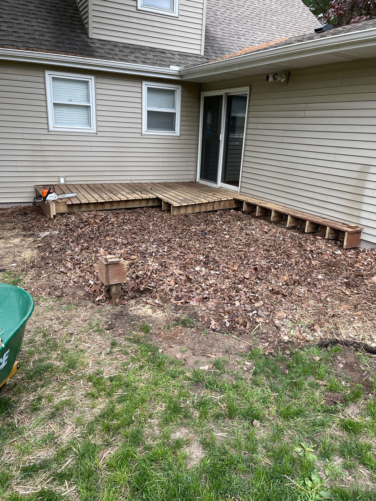 Deck stairs beside a cleared mulch bed along the siding