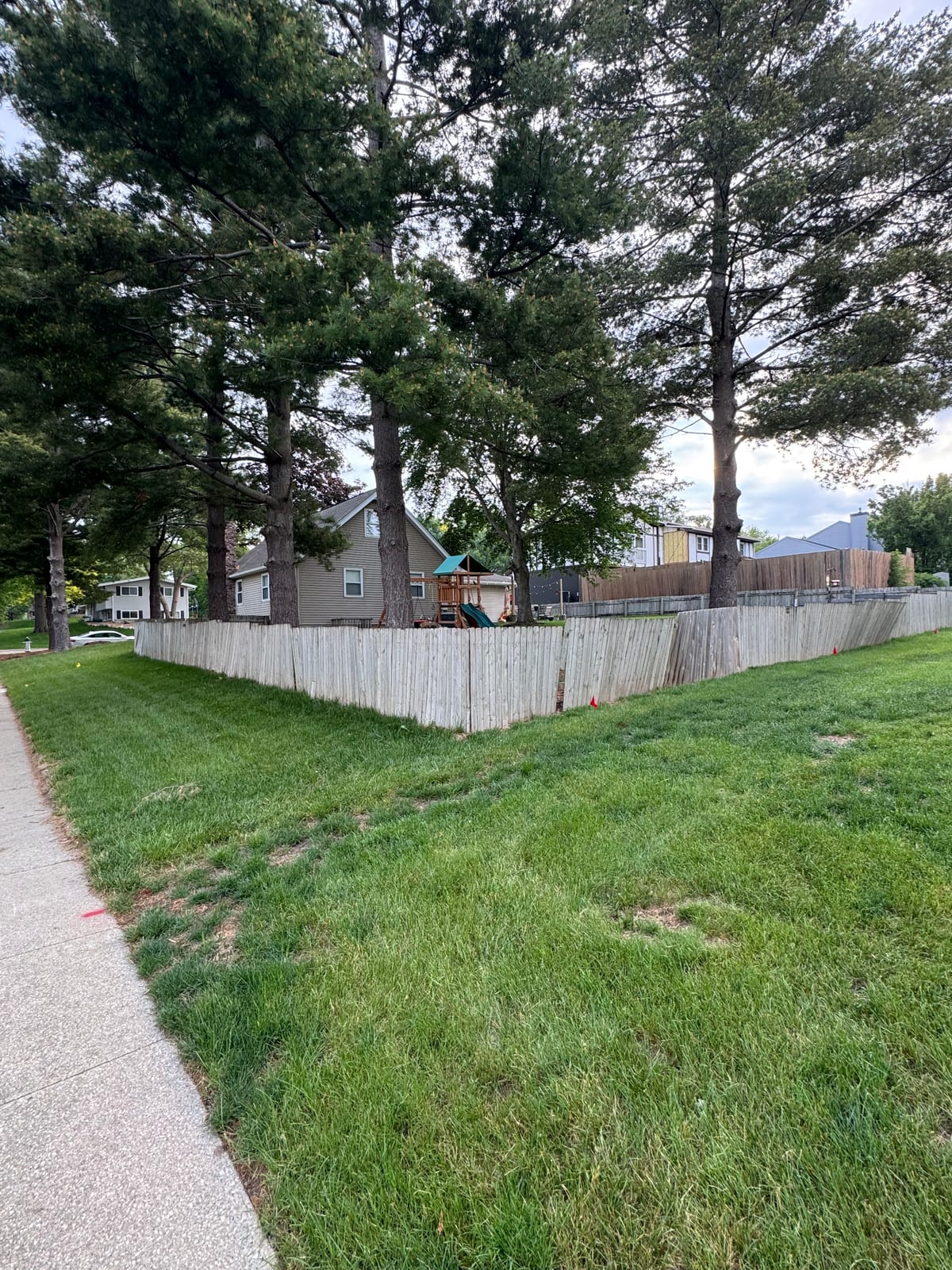 Sidewalk view of the backyard fence and neighboring houses