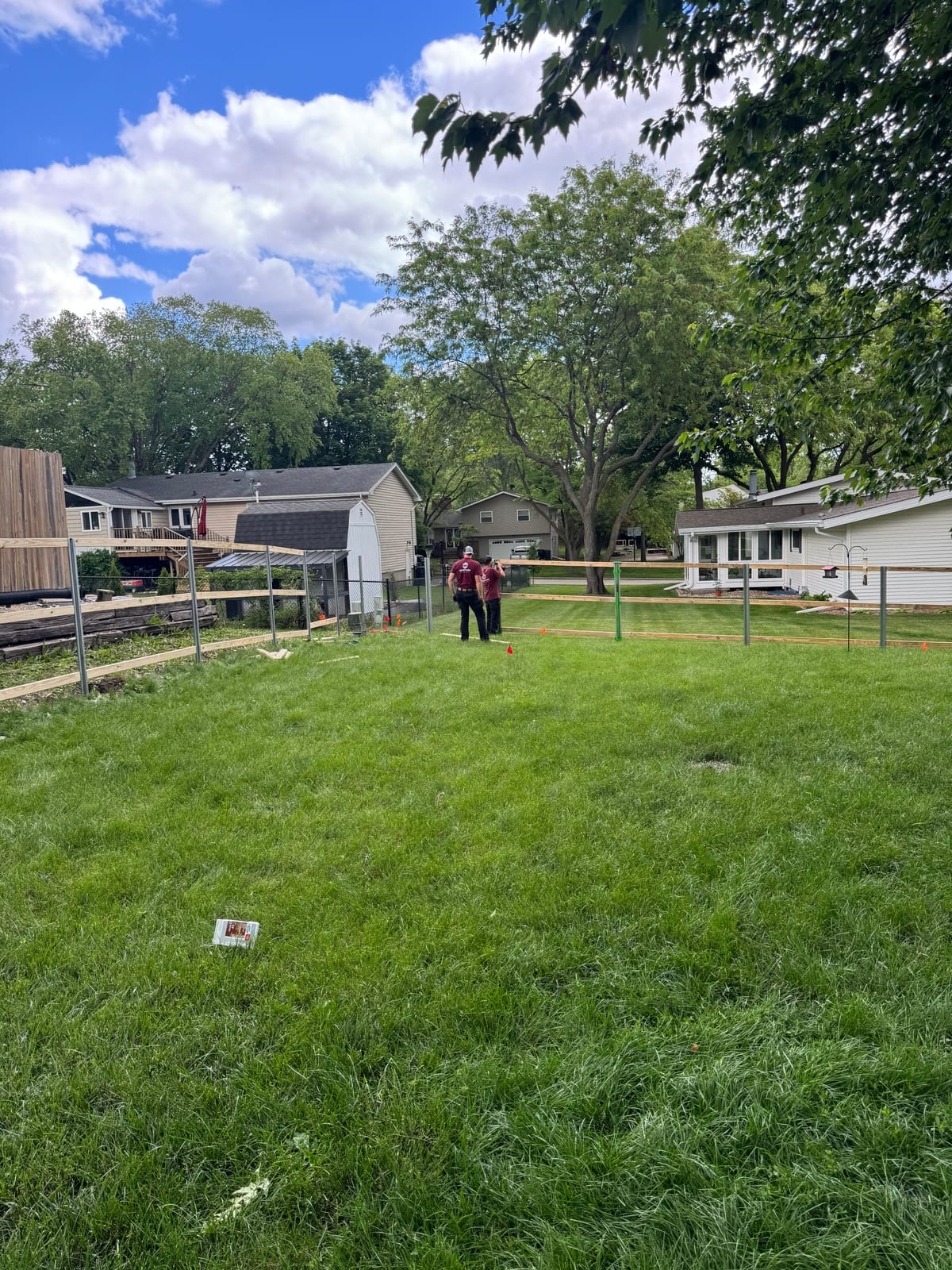 Lawn with new fence posts and the red riding mower